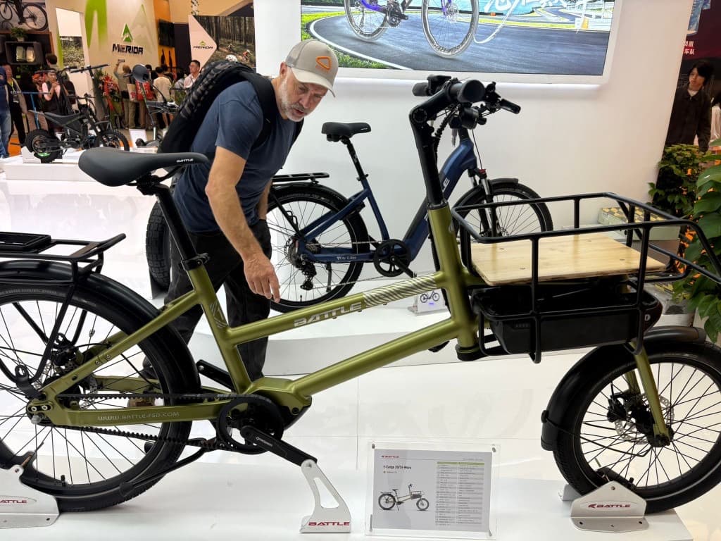 Wide view of Matt inspecting a cargo e-bike on the show floor